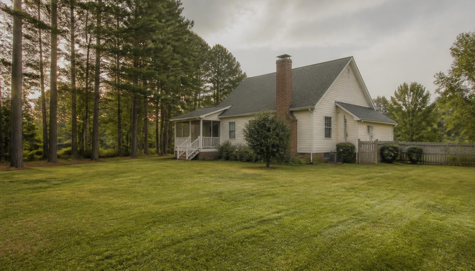 A single-family house on a large grassy lot bordered by pine trees in rural North Carolina, the kind of property typically served by an onsite septic system.